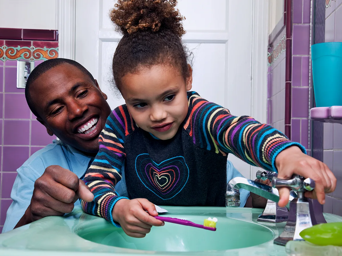 Summer habits. A child brushes their teeth with their parent. 