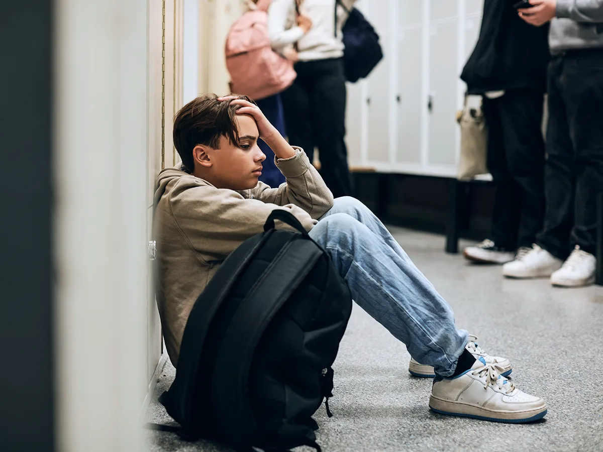 Does ADHD raise the risk of mental health issues?, kid lonely in a school sitting on the ground by his locker