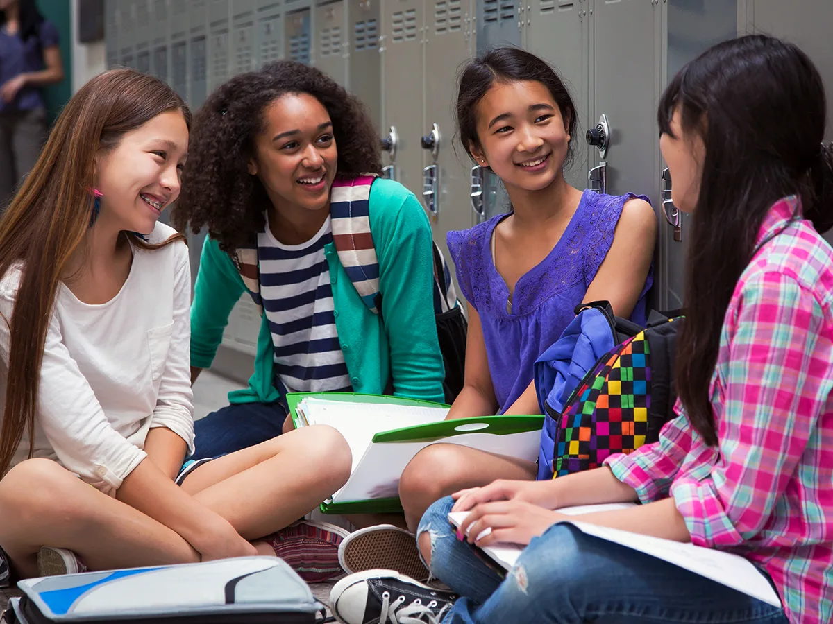 8 ways to help your middle-schooler connect with other kids. A group of tweens sit in the hallway at school. 