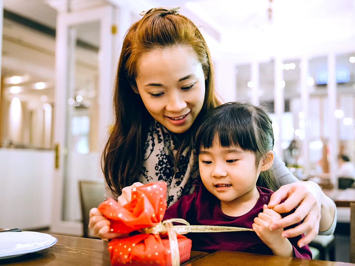 5 tips for picking gifts for your child, mother helping daughter open a present