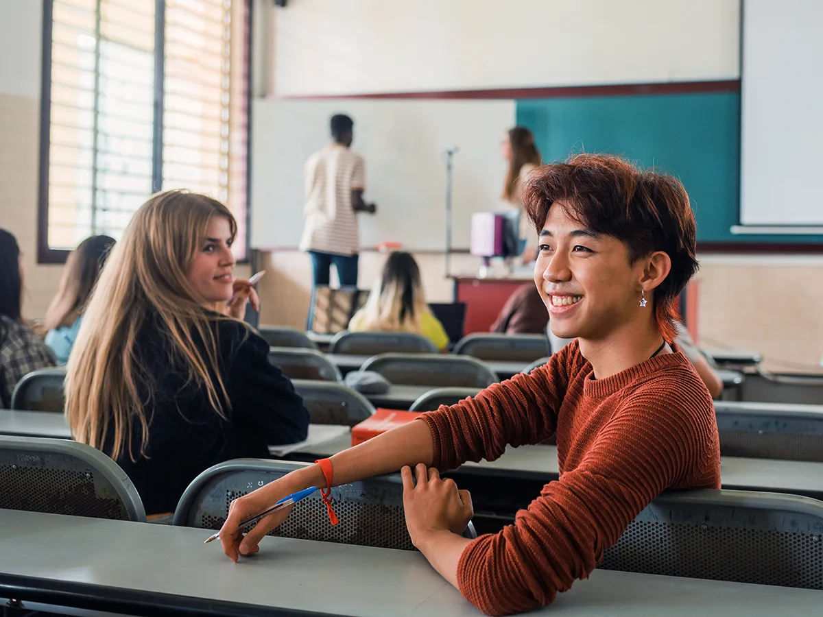 Hyperactivity in teens with ADHD: What it can look like. Student turns to classmate in the middle of class. 