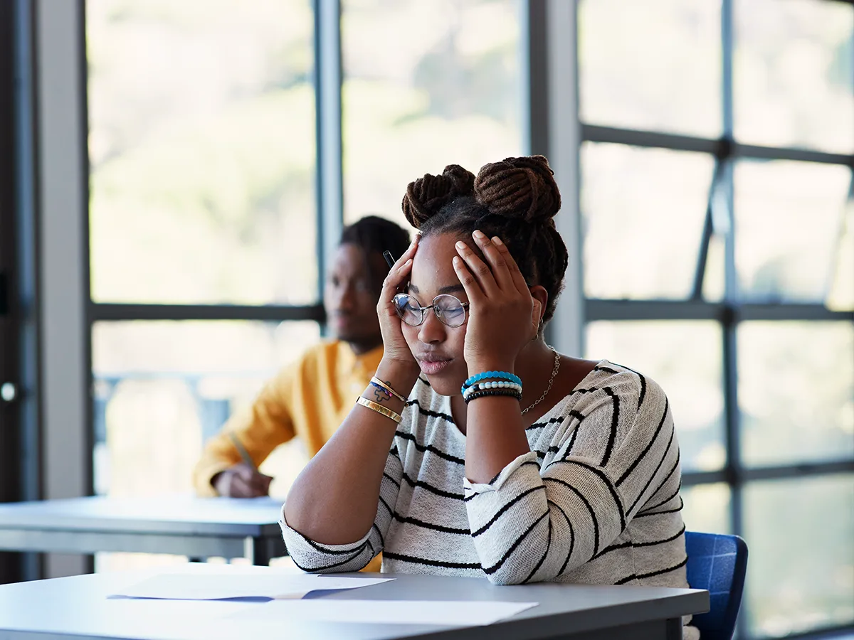5 stress factors for teens who learn and think differently, black girl sitting at a desk in school holding her head in stress
