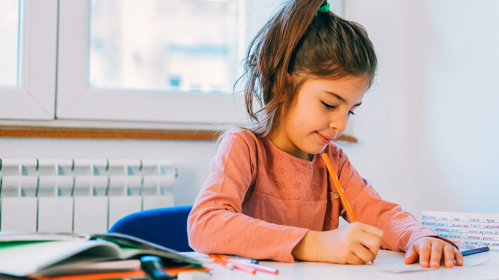 Un adulto ayuda a un niño que está escribiendo en una hoja de papel.