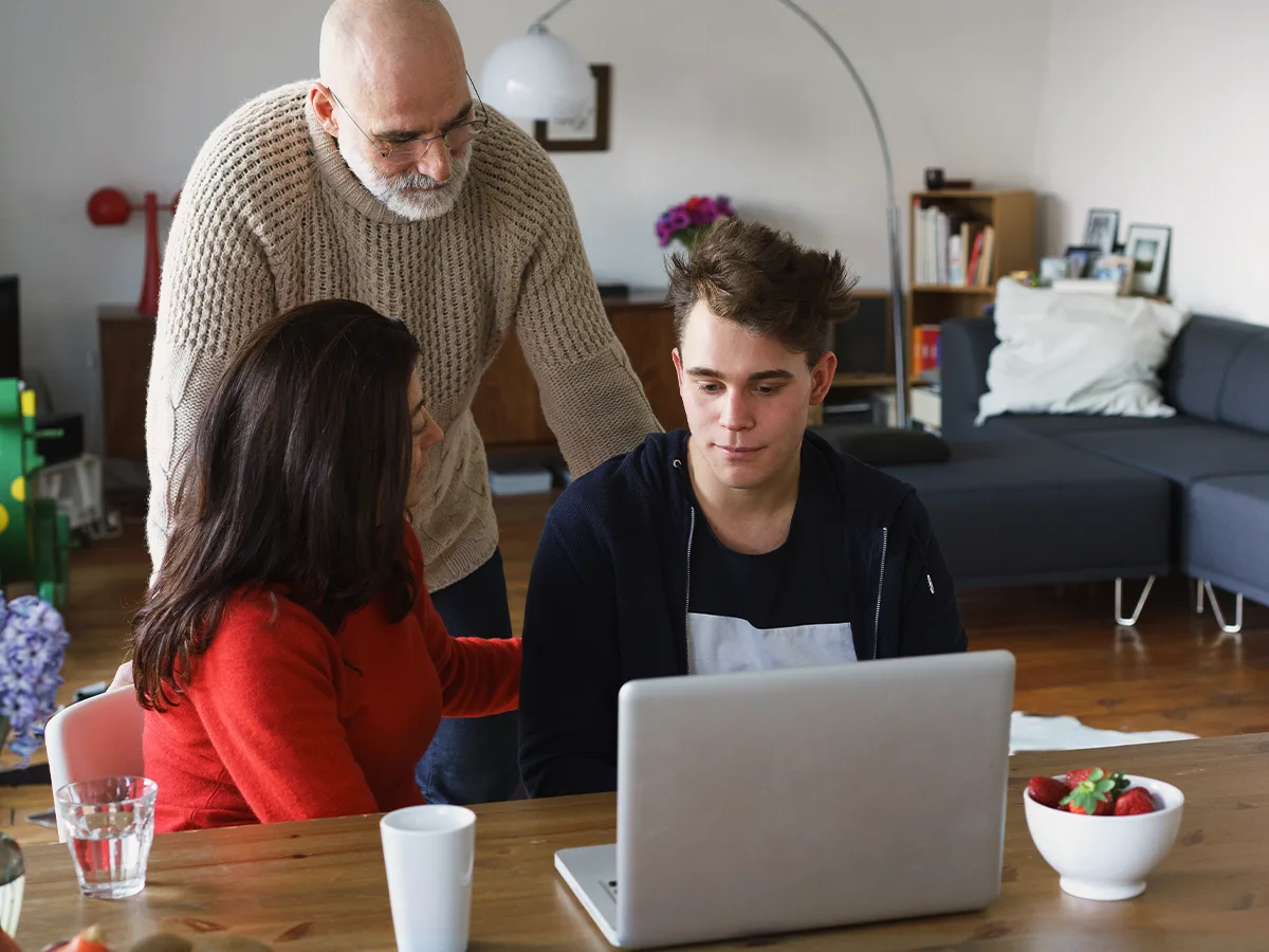 Executive function challenges and learning: 6 ways to help your child after high school. Parents speak to their adult child in front of a laptop. 