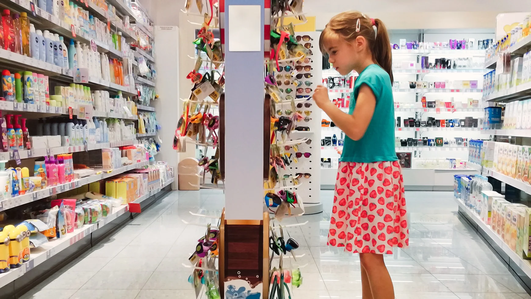 A young child looks at a rack of sunglasses in a store. 