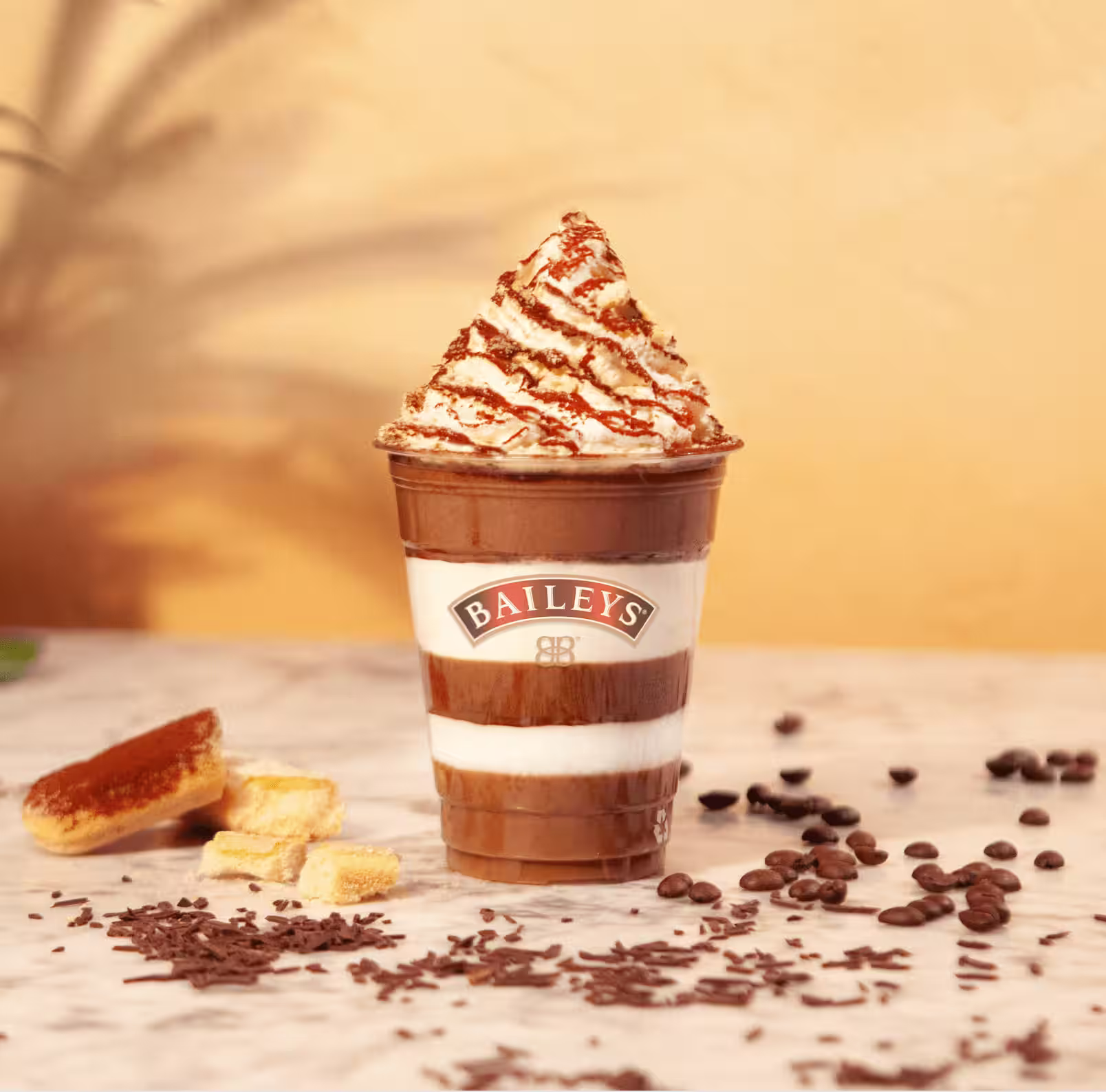 A Baileys Frozen Tiramisu drink layered with creamy mascarpone, topped with a swirl of whipped cream, cocoa powder, and a drizzle of chocolate sauce.