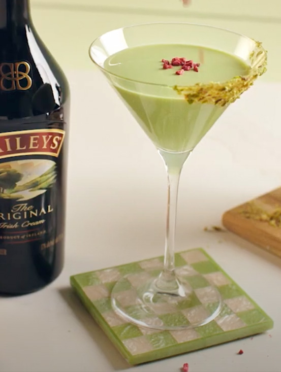 Martini Baileys Pistachio servi dans un verre à martini à côté d'une bouteille de crème irlandaise Baileys Original.