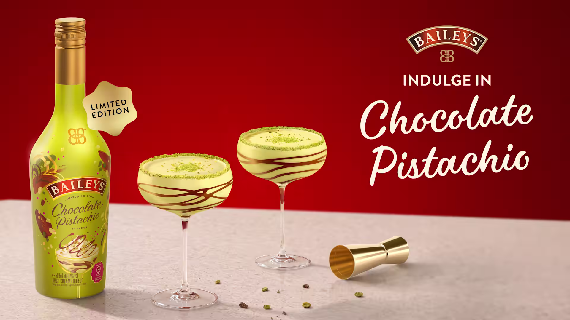 Een limited edition-fles Baileys Chocolate Pistachio met twee pistachecocktails, chocoladesaus en een pistachegarnering op een rode achtergrond.