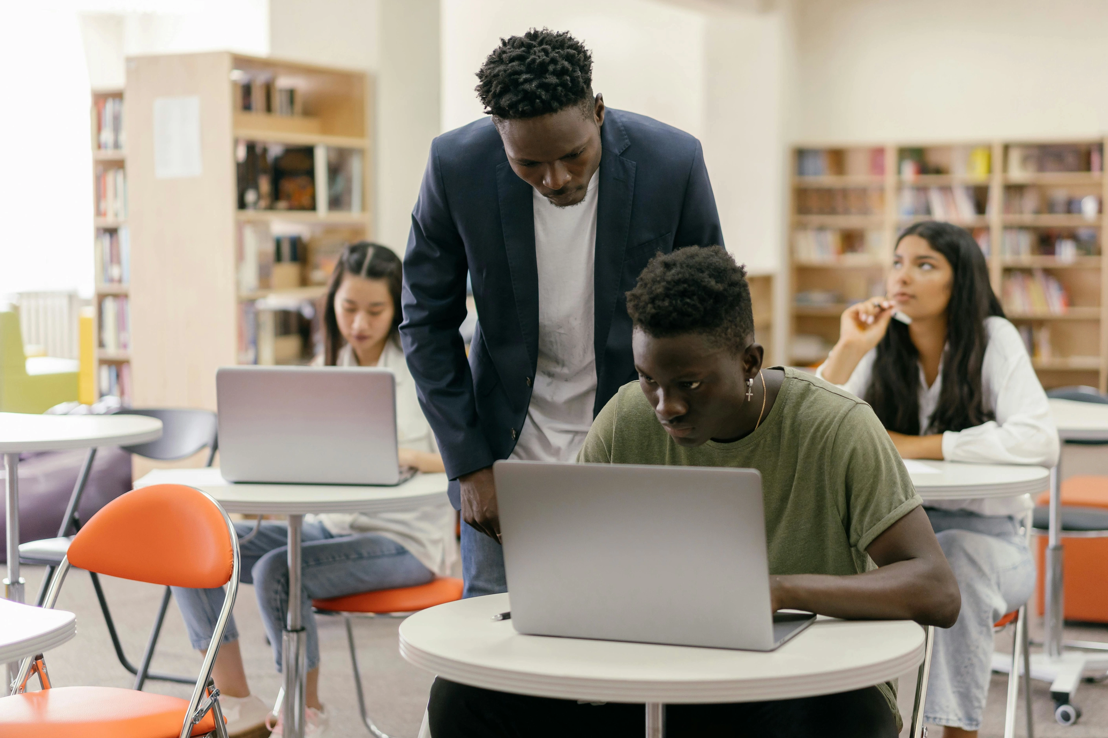 Three students are in a classroom thinking and working on their laptops