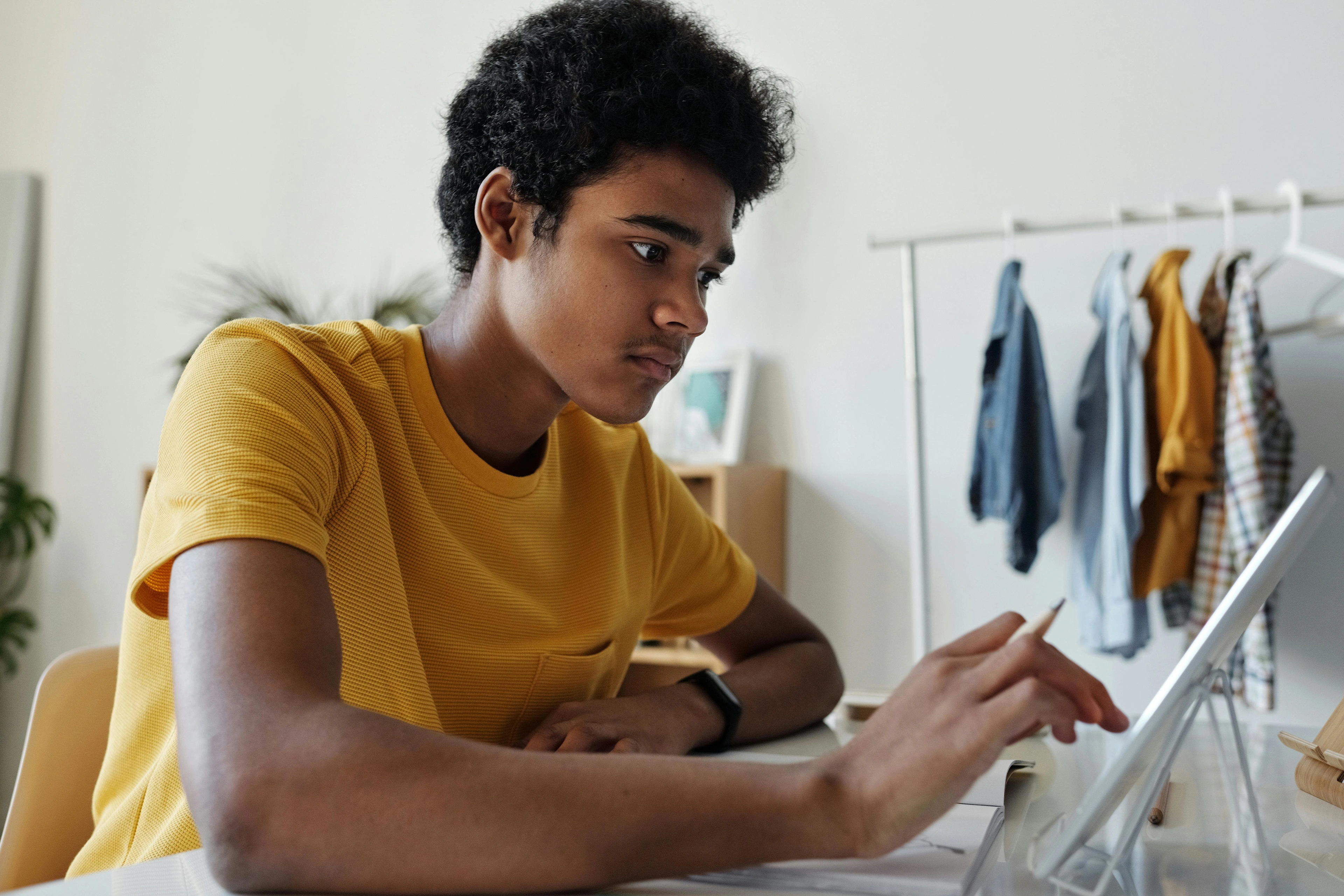 A young man is studying on his tablet while holding a pen