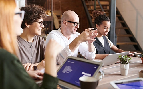 Group of people in a meeting and a woman is presenting to the team