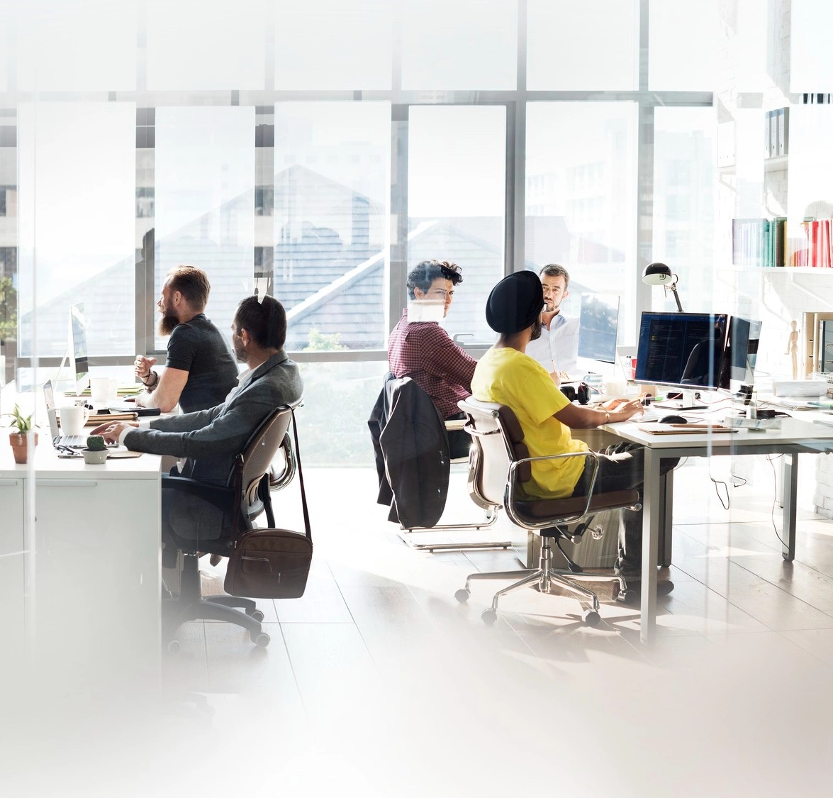 Een softwareteam aan het werk in een licht kantoor met open indeling, met code op een scherm