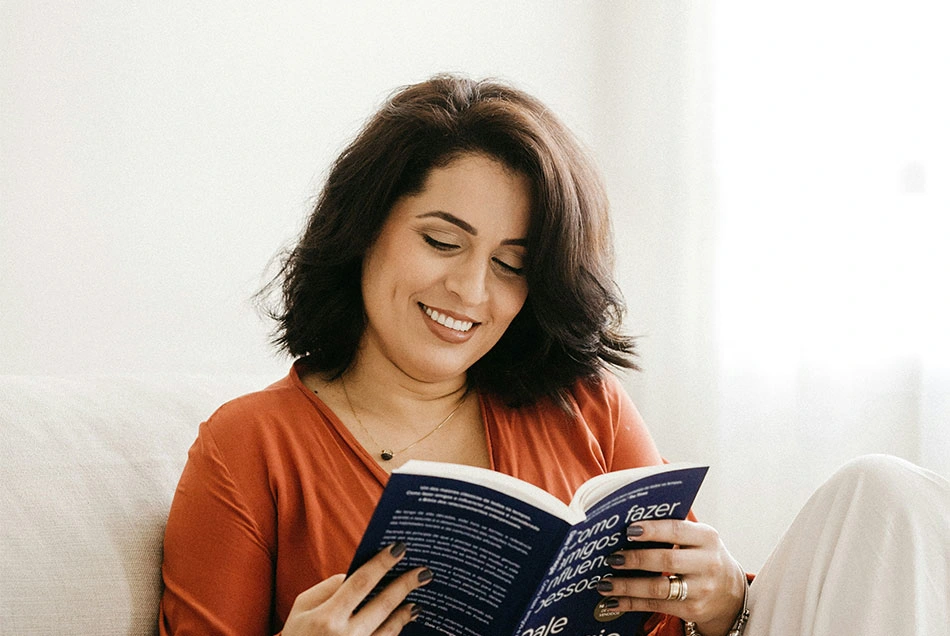 A woman smiling and reading her book relaxed