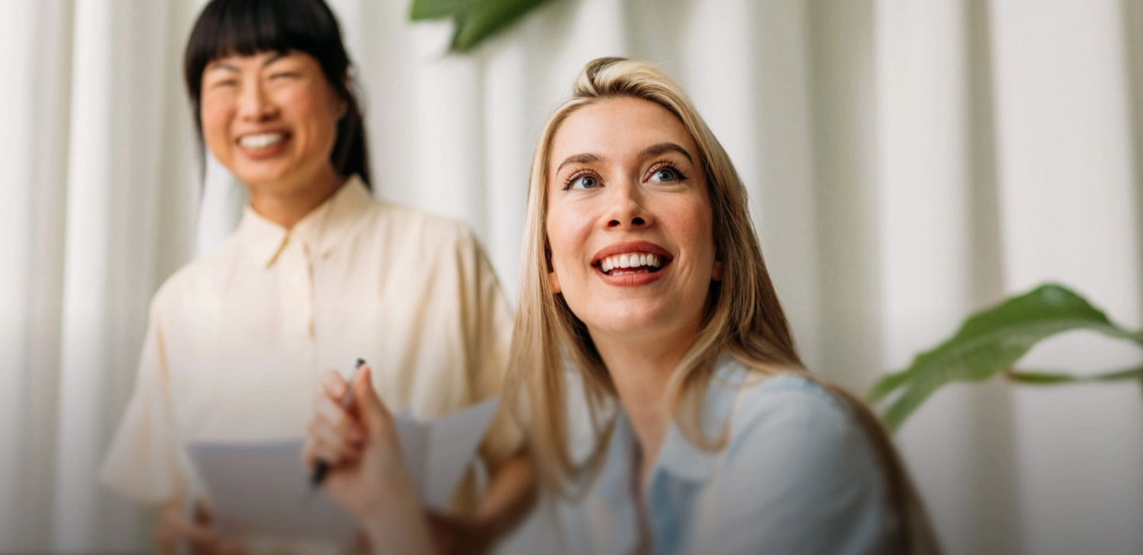 Deux collègues sourient et rient ensemble dans un bureau lumineux
