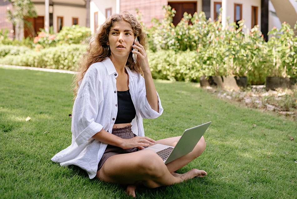 A woman working from her garden using a laptop and mobile phone.