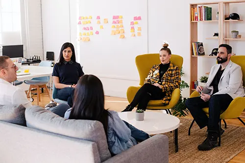 five persons having a group meeting in office space