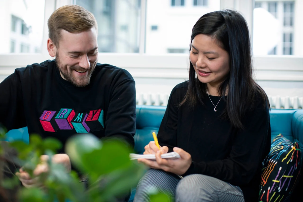 Two smiling people on a sofa talking during a meeting 