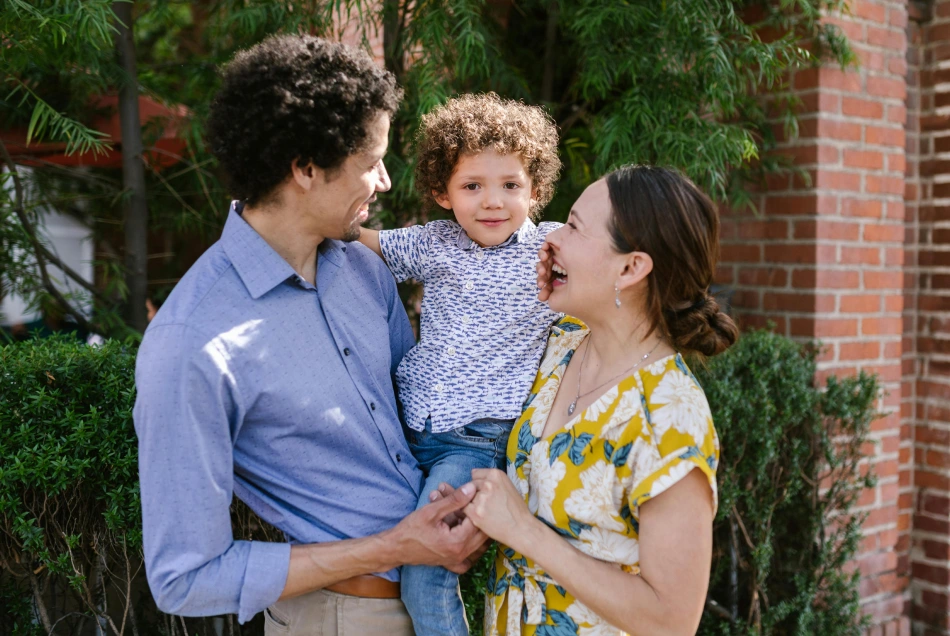 A couple is holding their child and smiling.