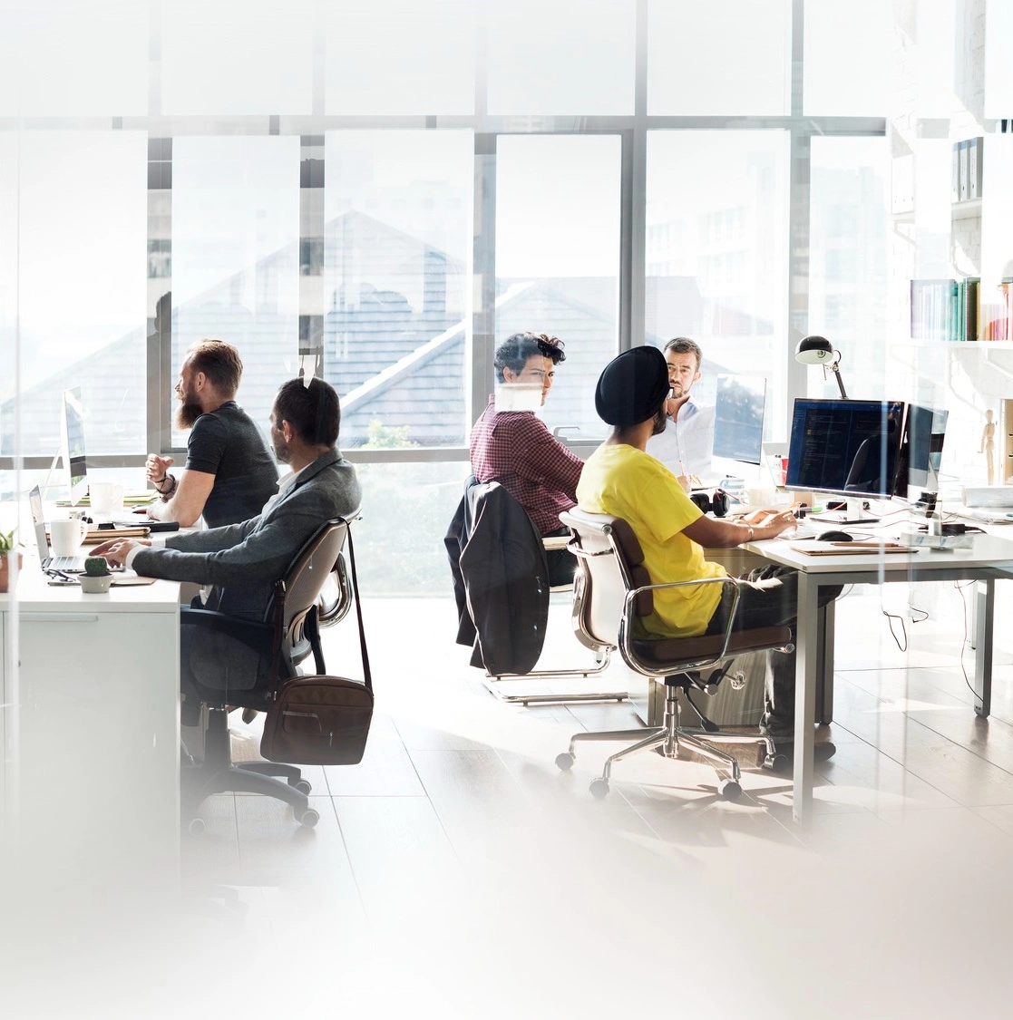 Een softwareteam aan het werk in een licht kantoor met open indeling, met code op een scherm