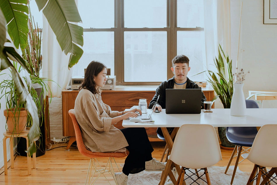 Two people working on a large desk remotely or from home