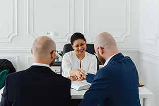 Lawyer shakes hands with his clients sitting in their office at the table