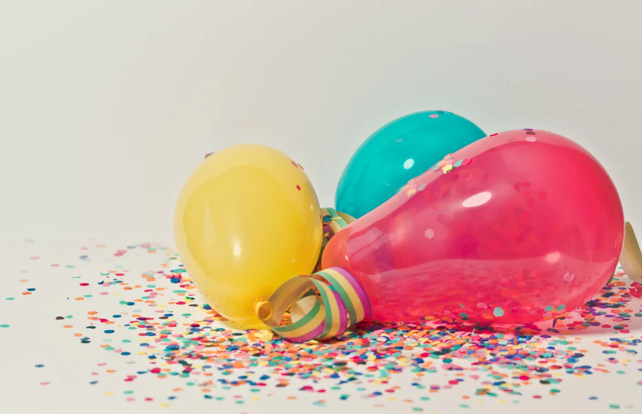 Gelber, roter und grüne Luftballon und buntes Konfetti auf dem Boden