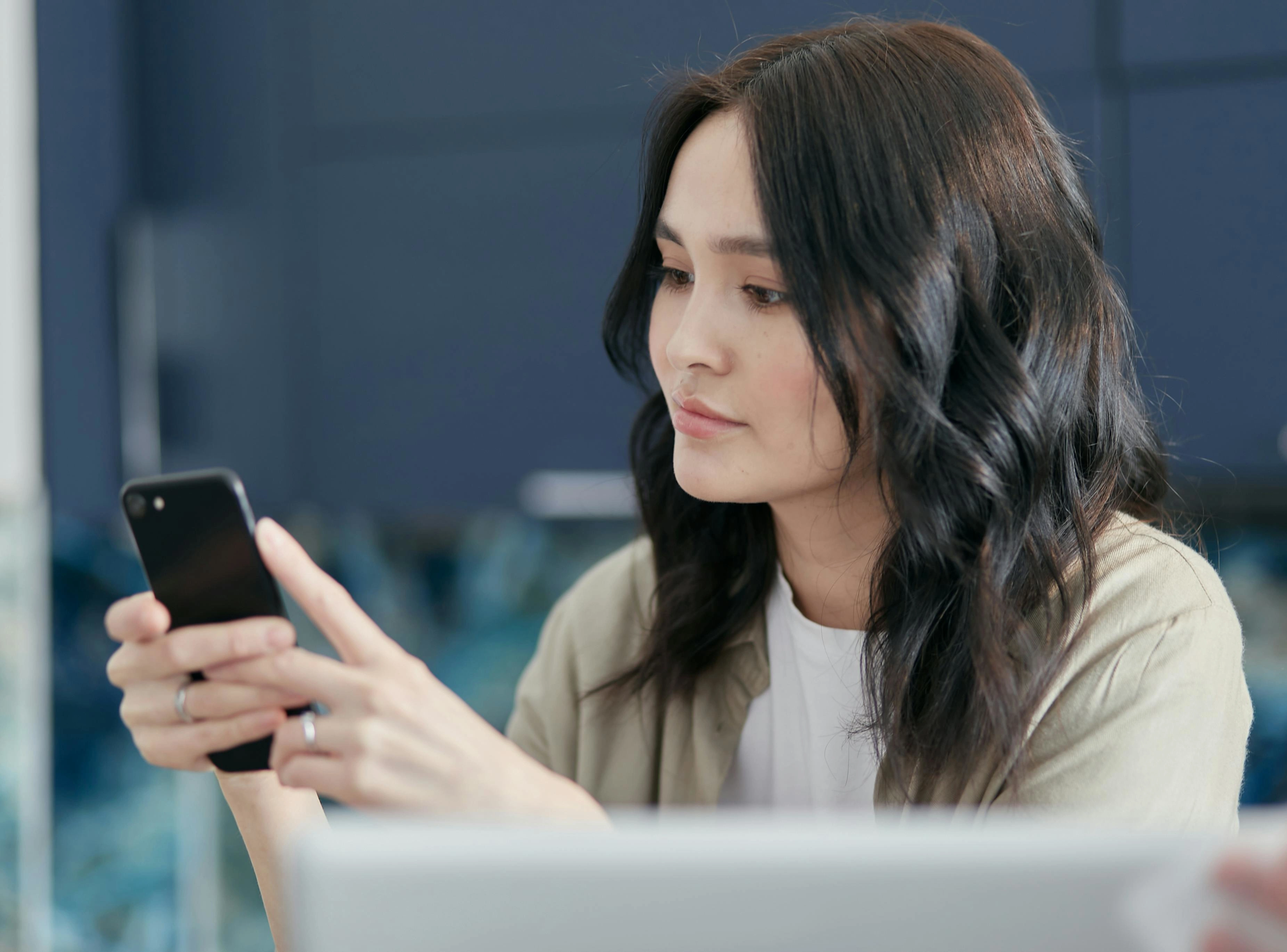 A woman is sitting and using her phone