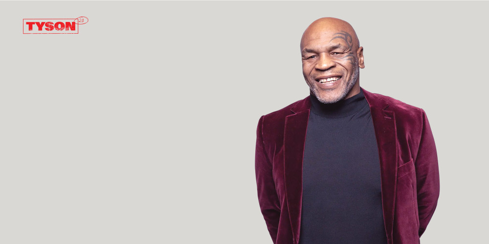 Tyson Vapes brand image. Mike Tyson in a velvet suit, smiling.