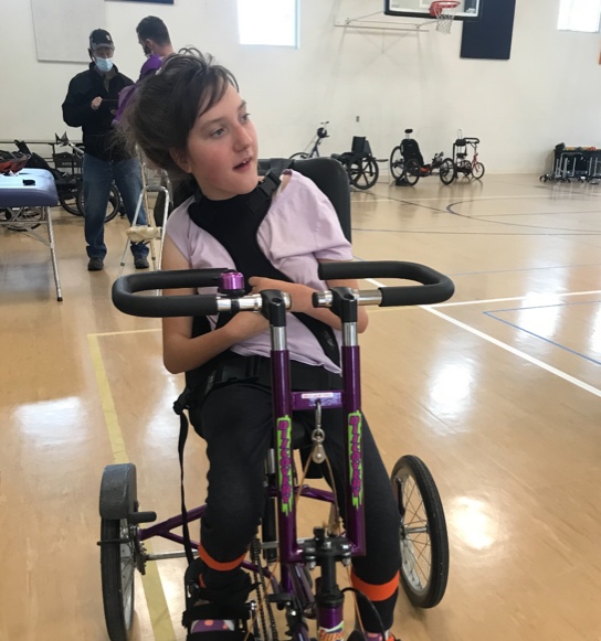 Lucy using a bicycle during therapy at a gym.