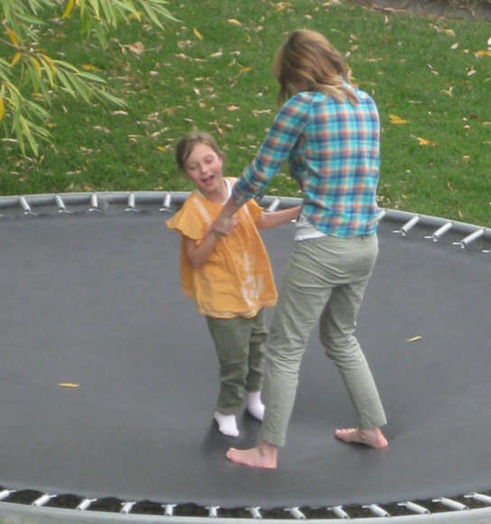 Lucy on trampoline jumping with her brother.