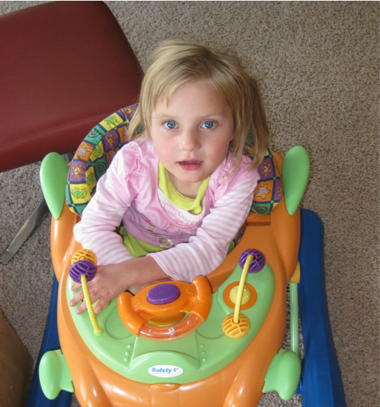 Lucy as a toddler playing in a sit-to-stand center.