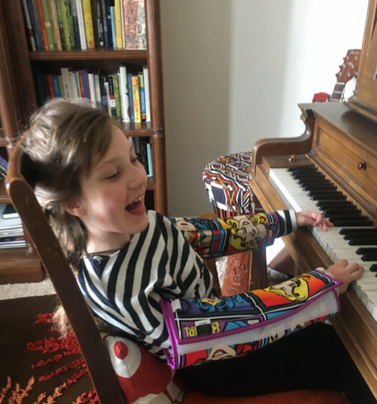 Lucy smiling and playing the piano.