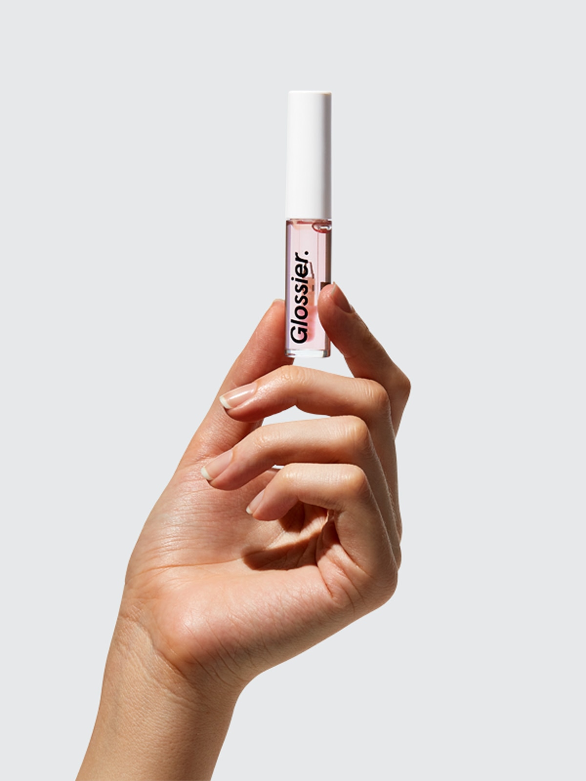 A hand holding a 0.14 fl oz (4.2 ml) tube of Glossier Lip Gloss