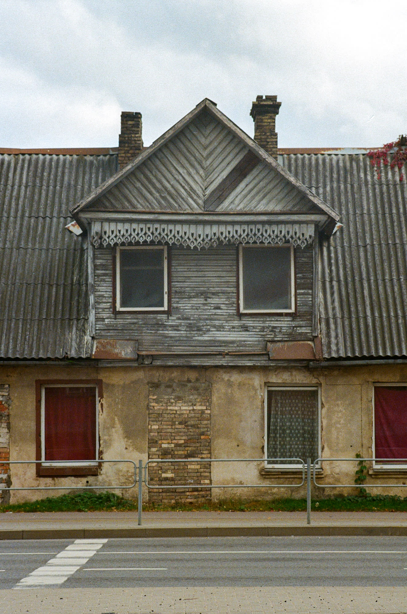 House with interesting colors of red and grey. Empty road at the very bottom of the image.