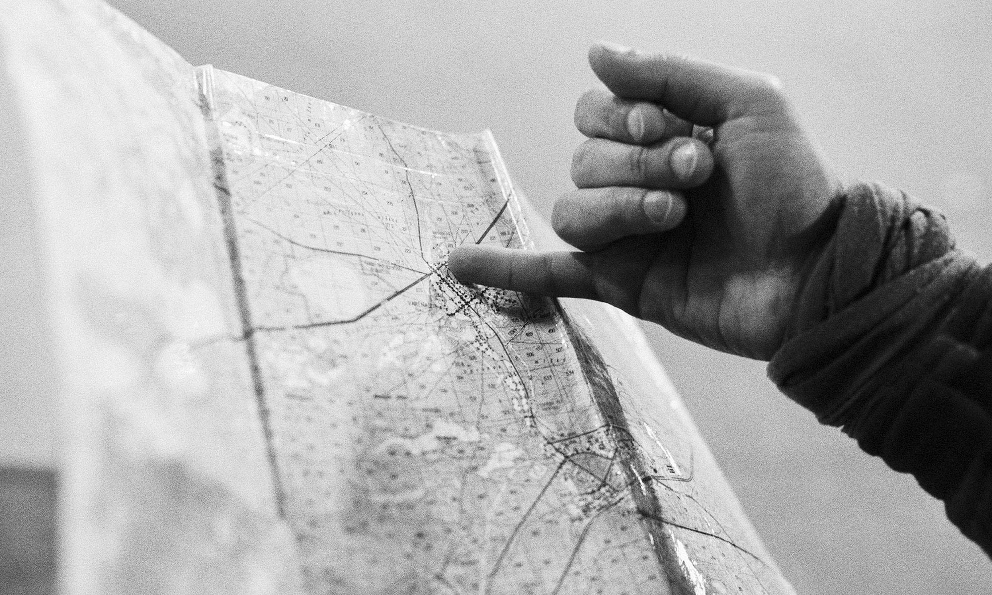 Photograph of finger pointing at map. Black and white, taken by me.