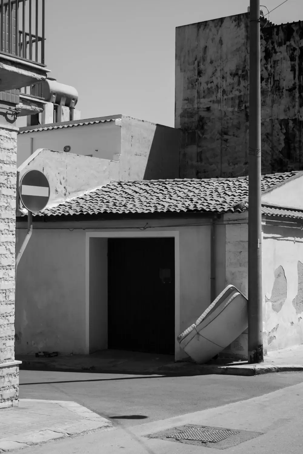 View of an empty street with sleeping mattress leaned on the corner of the wall.