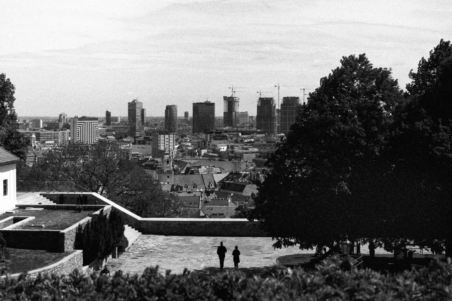 In Bratislava, shadowed couple walking against whole city background, cranes, etc.