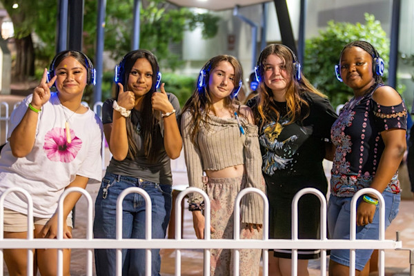 Five young people attending a silent disco wearing headphones