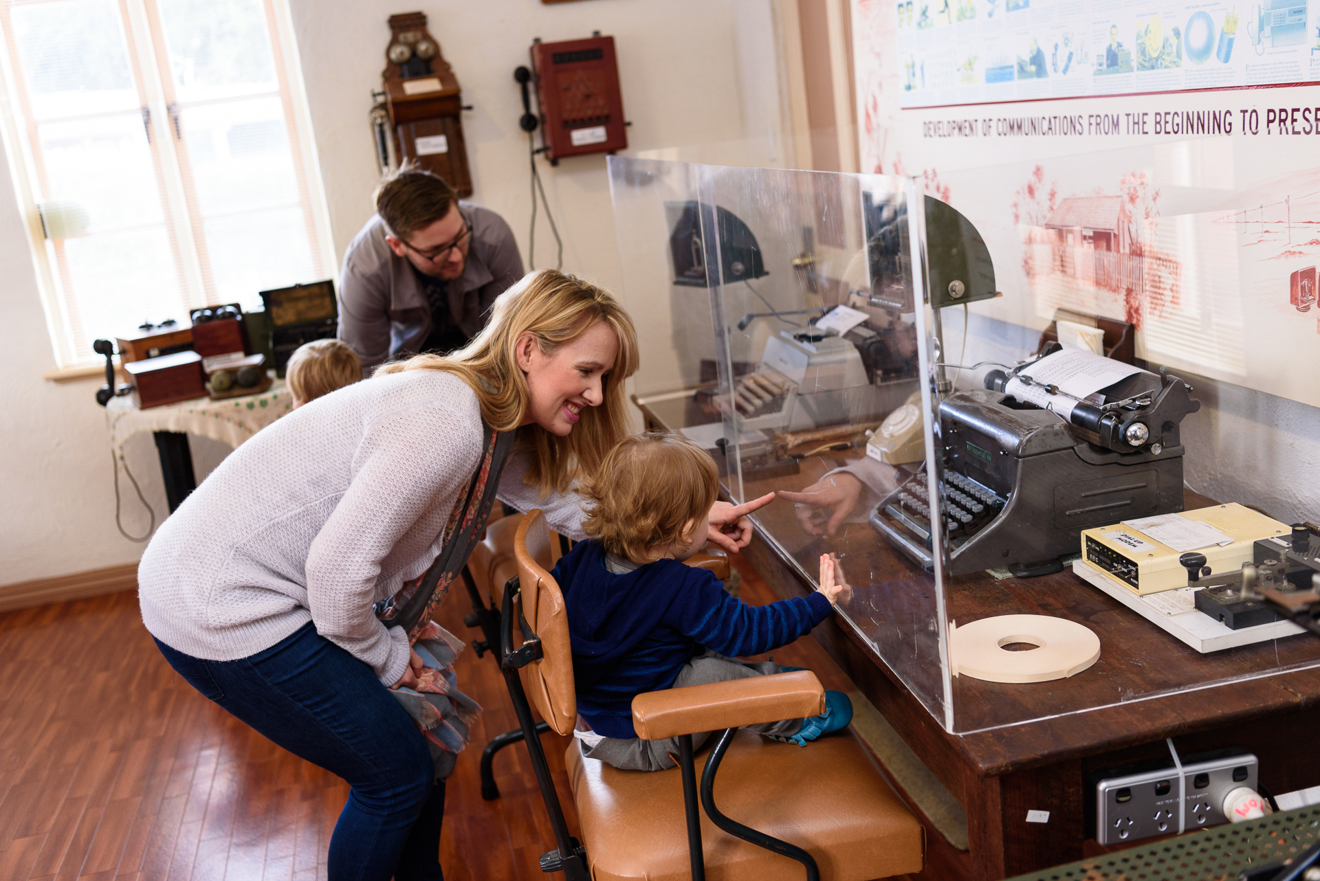 A family of two adults and two children looking at an old tractor.