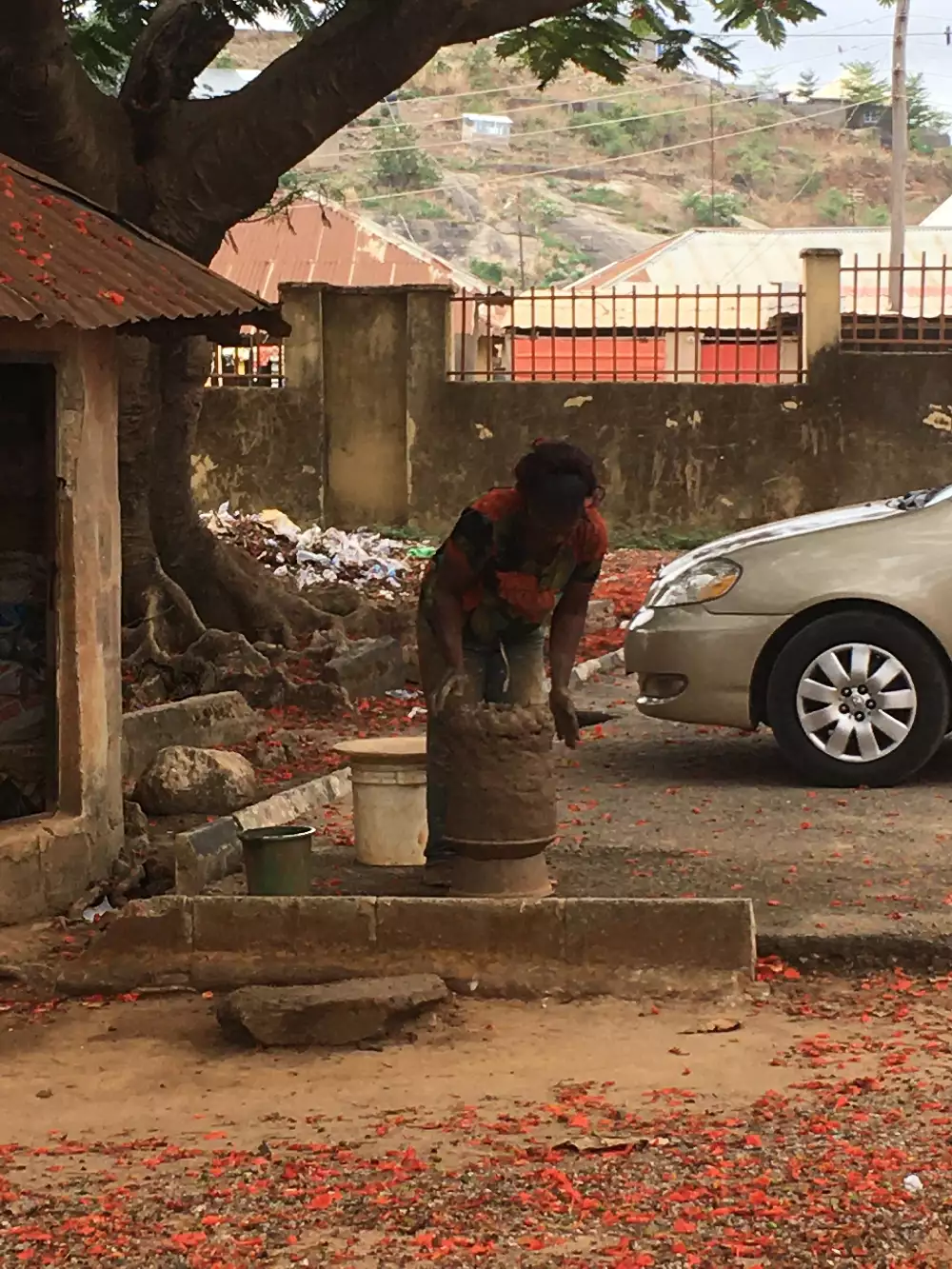 An outdoor scene with a person working with clay next to the road