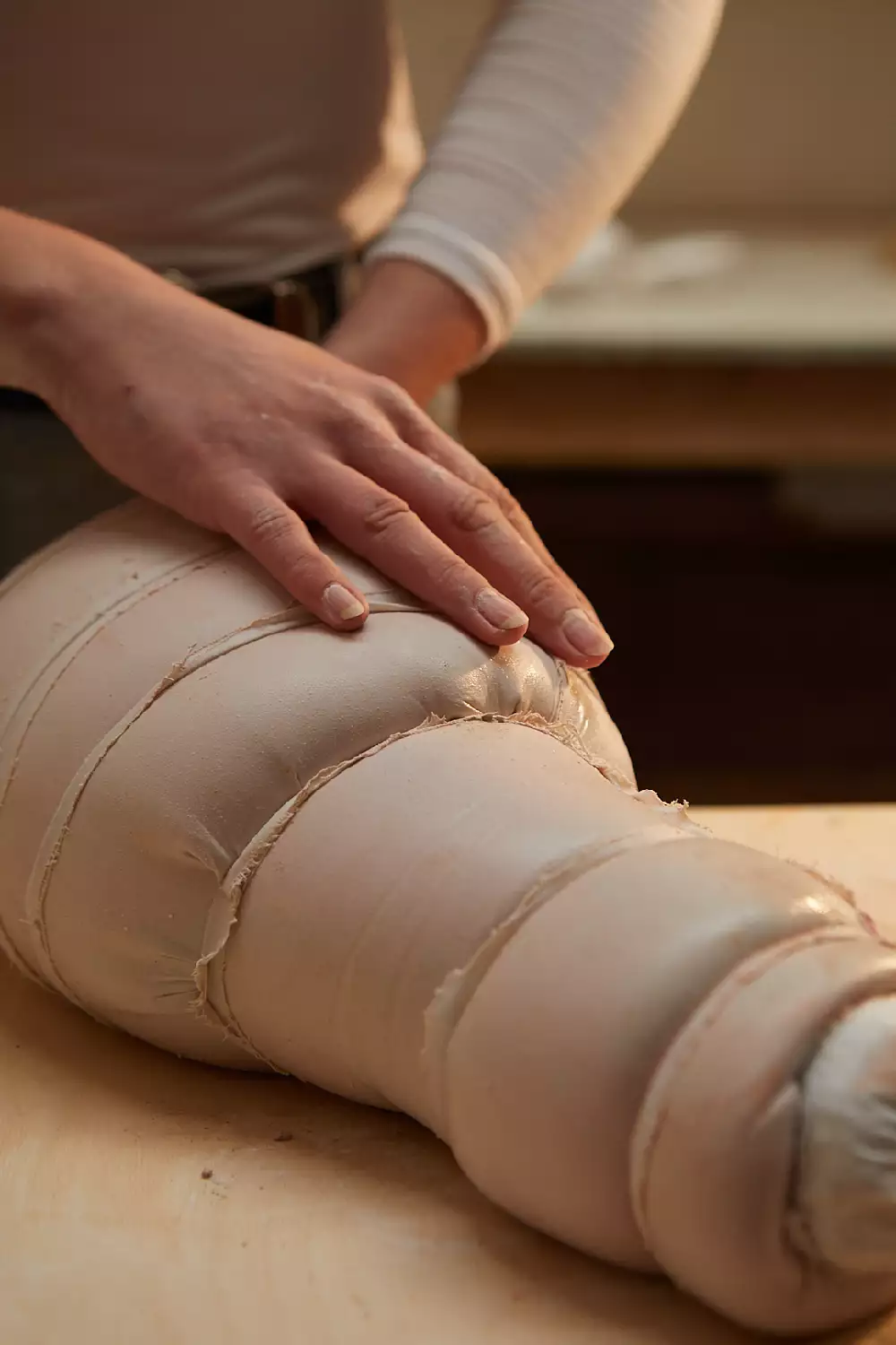 Image shows a close up of the artists hands working on a sculpture