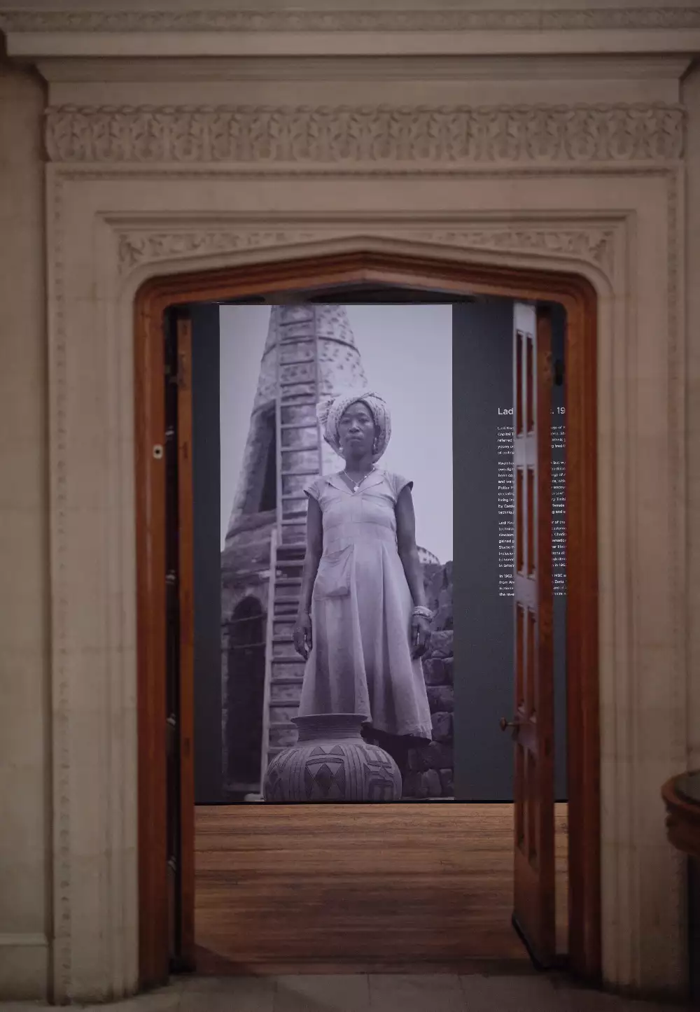 Archival photograph of Ladi Kwali, printed out large scale on the wall, framed by a doorway entrance to the room