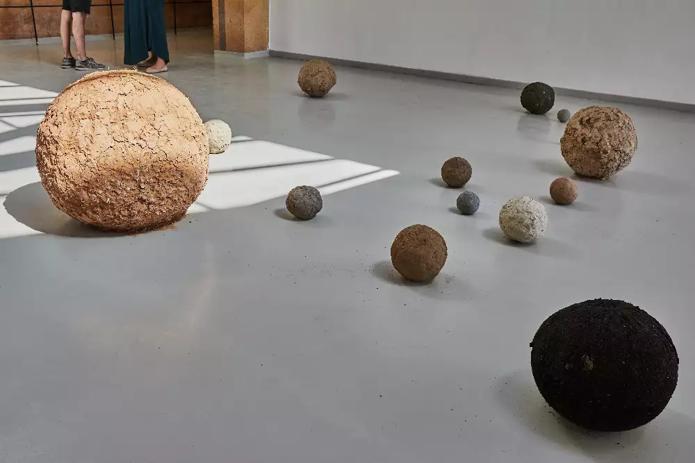 Dried out soil in the shape of balls of varying sizes on the floor of the gallery