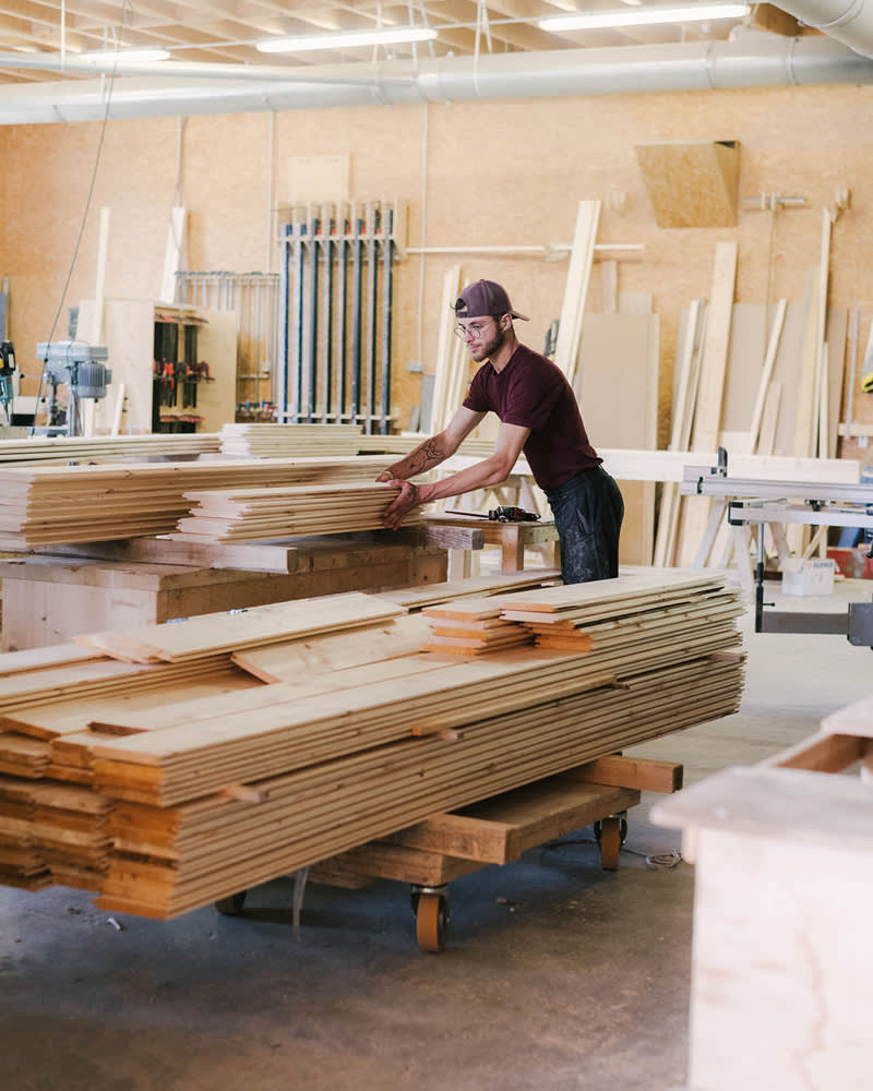 Un menuisier range des planches de bardage dans un atelier