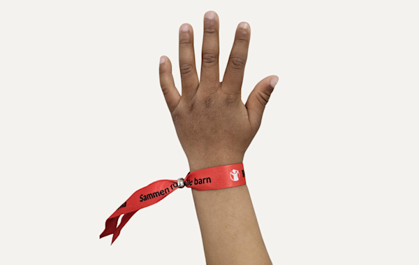 Et rødt armbånd med Redd Barnas logo og teksten «Sammen for alle barn»