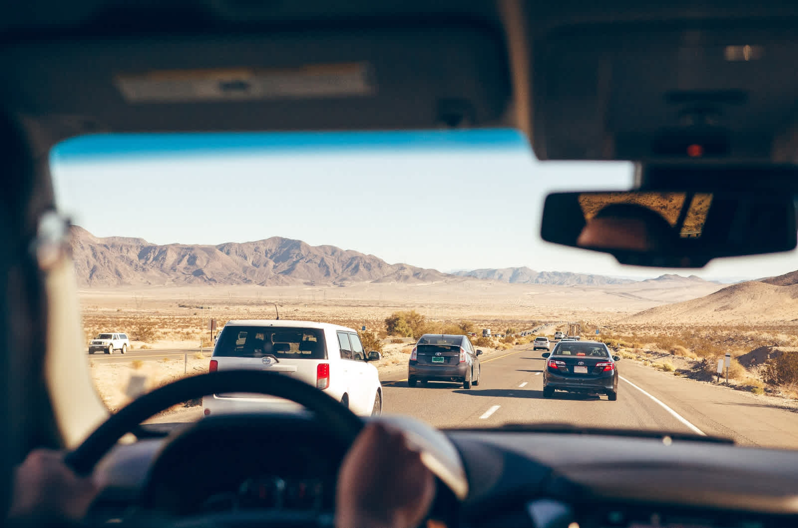 Desert landscape and highway are visible through windshield