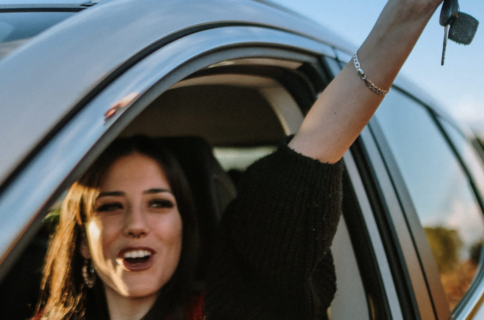 Happy young driver holds keys up in the air