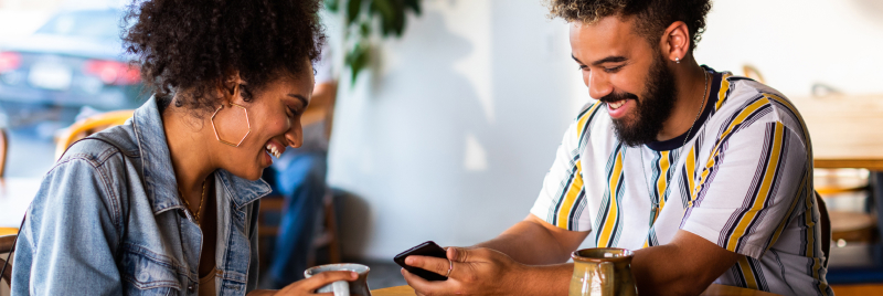 Man and woman sitting at table reviewing full coverage car insurance rates on a mobile phone