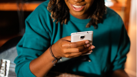 Woman holds a mobile phone in her hand managing her car insurance coverage