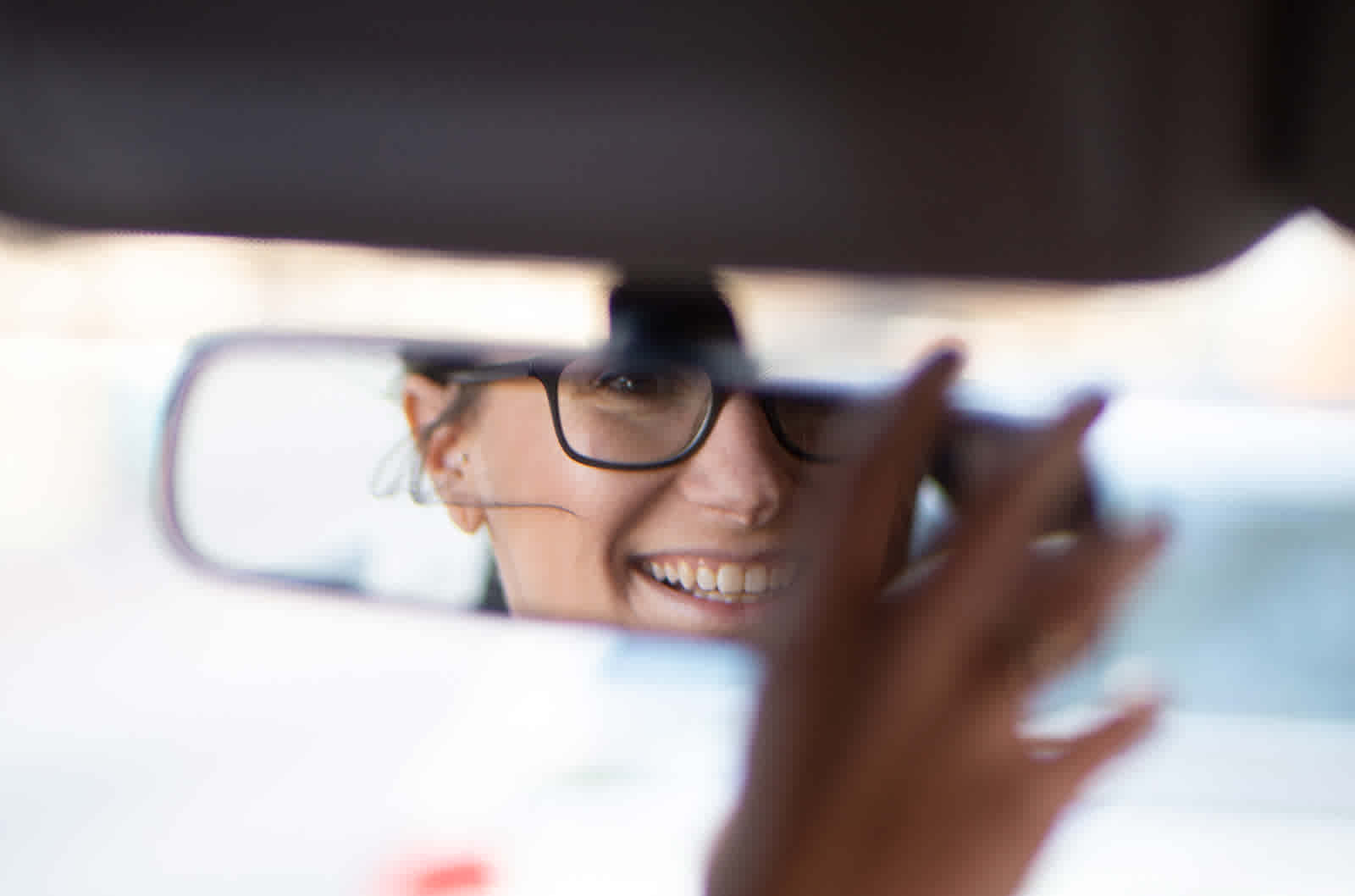Woman smiles into rearview mirror
